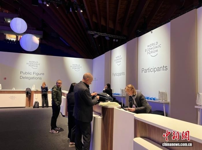当地时间1月19日，世界经济论坛2026年年会在瑞士东部小镇达沃斯拉开帷幕。图为参会代表领取参会证件。