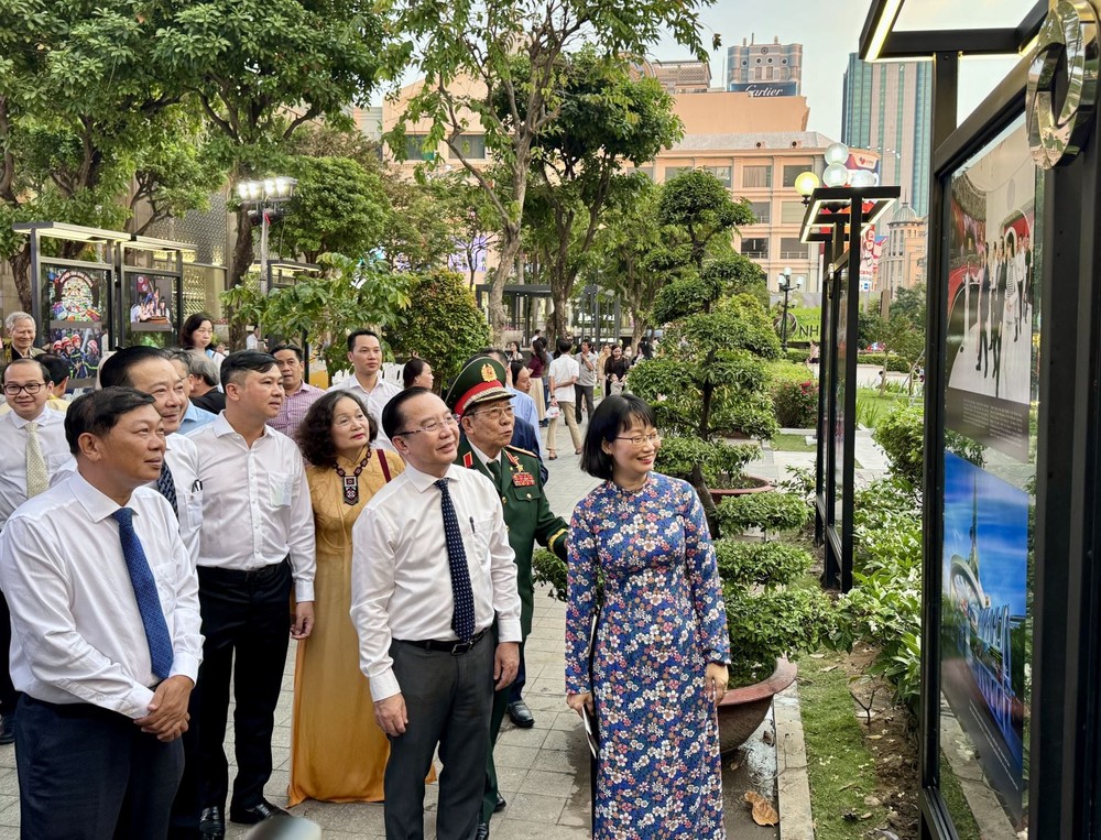 代表与嘉宾聆听主题为“在党的旗帜下稳步前行——胡志明市闪耀光彩”的摄影展讲解。