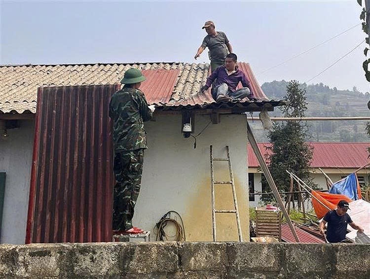 老街省军事指挥部干部、战士协助北河乡居民修复因冰雹和强风暴受损的屋顶。