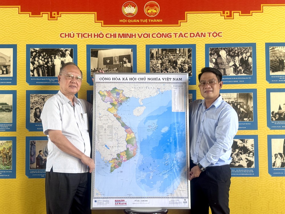 《西贡解放报》华文电子报采编部主任文忠孝（右）向穗城会馆理事长卢耀南赠送越南地图。
