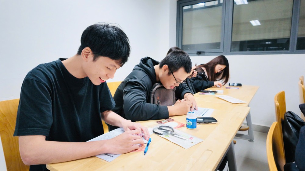 学生用造型压笔在银色锡纸上勾勒秦汉器物纹样。