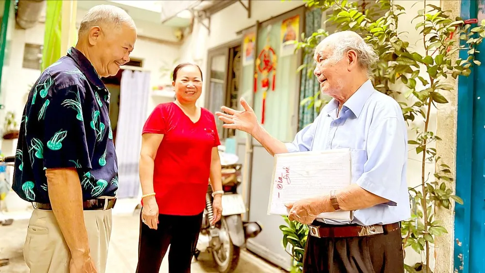 Ông Nguyễn Khắc Êm, nguyên tổ trưởng tổ dân phố 29, khu phố 3, phường Bến Nghé, quận 1 (TPHCM) trao đổi với người dân trong khu phố. Ảnh: THÁI PHƯƠNG