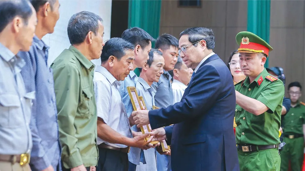 Thủ tướng Phạm Minh Chính trao thông báo kết quả giám định ADN hài cốt liệt sĩ đến đại diện gia đình liệt sĩ tại hội nghị. Ảnh: VIẾT CHUNG 