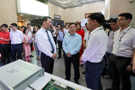 Minister of Information and Communications Nguyen Manh Hung paid a tour to ‘Make in Vietnam’ technological products in an exhibition in the framework of the conference. (Photo: SGGP)