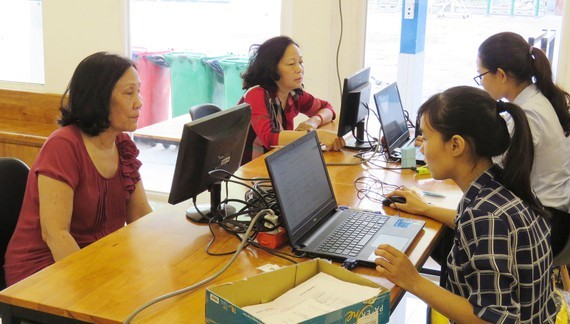 Staffs and teachers at primary and junior high schools in Tan Binh District are present to help parents without laptops at homes to register online at schools (Photo: SGGP)