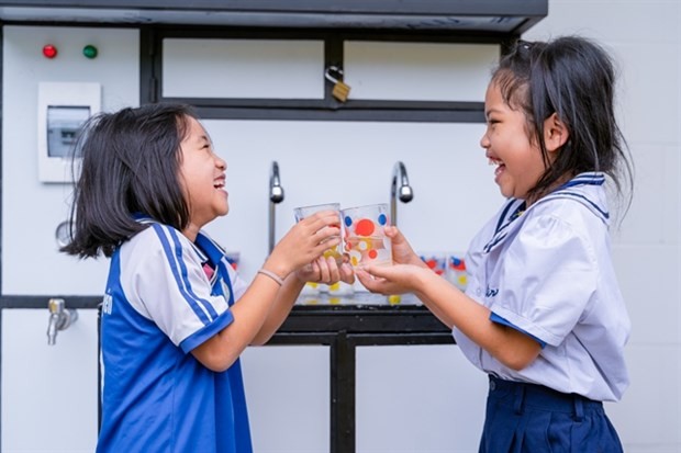 Two school students in Quang Nam Province enjoy clean water system at a primary school. Five systems were installed at five remote schools by Lifestart Foundation. (Photo courtesy of Lifestart Foundation)