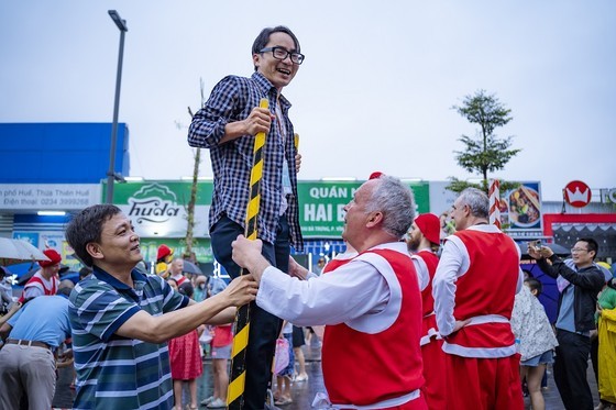 Belgian artists instruct a man to walk on tall sticks