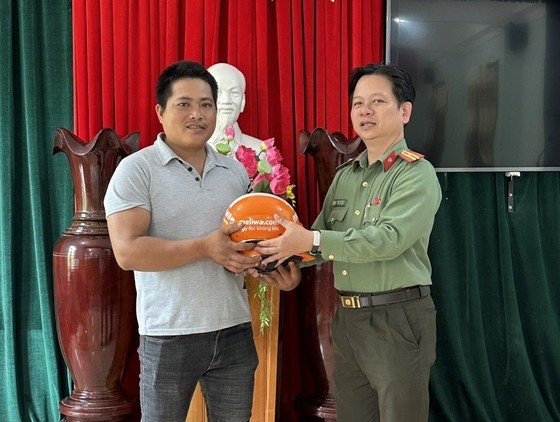 A representative of the local Police Station gives a gift to Mr. Le Van Hoi