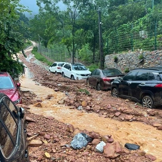 Cascading soil and rocks bury cars on the road to Ban Tien Lake in Hanoi yesterday