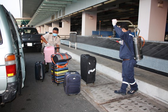 Medical workers spray with Chloramin B disinfectant for passenger's luggage