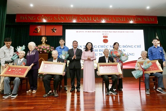 Chairwoman of the City People’s Council Nguyen Thi Le presents 75-year Party membership badges to old Party members of District 3. (Photo: Dung Phuong)