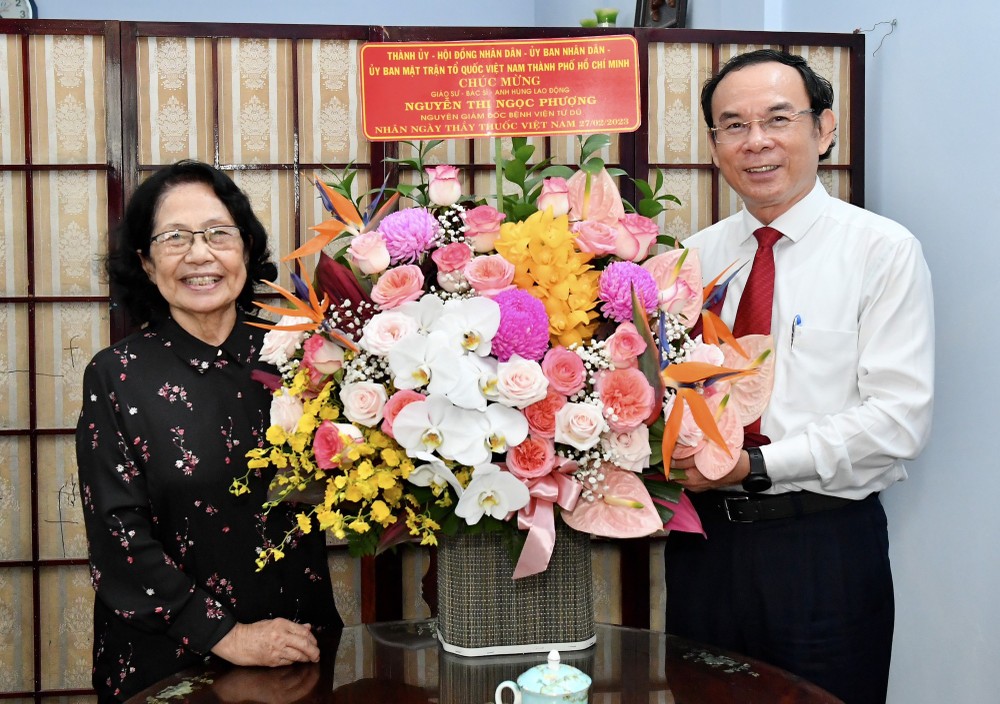 Secretary of the Municipal Party Committee Nguyen Van Nen presents flower to Prof. Doctor Nguyen Thi Ngoc Phuong, the Hero of Labor, former Director of Tu Du Hospital. (Photo: Viet Dung)