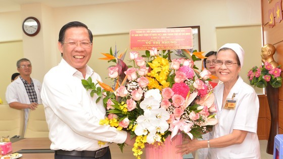 Chairman of Ho Chi Minh City People’s Committee Phan Van Mai presents a flower basket to Assoc. Prof. Dr. Doctor Vu Thi Nhung, former Director of Hung Vuong Hospital. (Photo: Cao Thang)