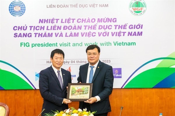 Vice Chairman of the Vietnam National Olympic Committee and General Director of the Vietnamese Sports Administration Dang Ha Viet (R) presents a picture to FIG President Morinari Wantanabe (Photo: VNA)