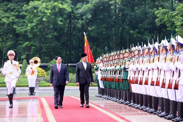 PM Pham Minh Chinh (L) and his Malaysian counterpart Anwar Ibrahim review the guard of honour at the welcome ceremony in Hanoi on July 20. (Photo: VNA)