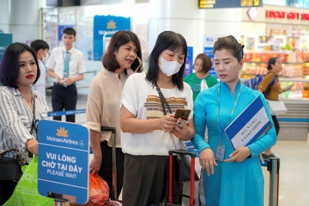 An airport staff supports an air passenger to use the VNeID. (Photo: VietnamPlus)