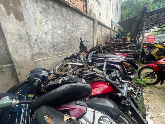 Numerous abandoned motorbikes are in a parking lot.