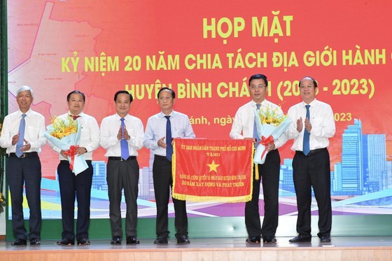 The Ho Chi Minh City People's Committee offers the traditional flag to the Party Committee, government and people of Binh Chanh District. (Photo: Viet Dung)