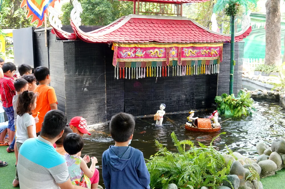 Các em thiếu nhi và phụ huynh bị cuốn hút vào các tiết mục biểu diễn múa rối nước đặc sắc. Ảnh: THÚY BÌNH