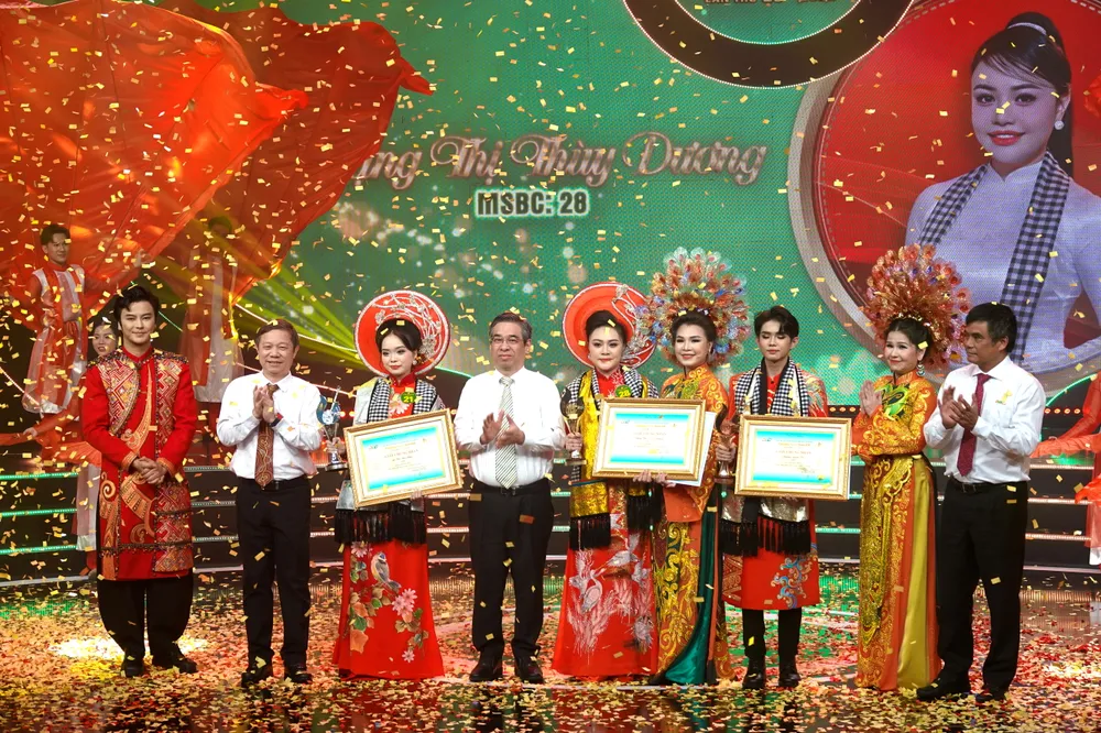 Phó Bí thư Thành ủy, Chủ tịch UBMTTQ Việt Nam TPHCM Nguyễn Phước Lộc, Trưởng Ban Tuyên giáo và Dân vận Thành ủy TPHCM Dương Anh Đức và Tổng Giám đốc Đài Truyền hình TPHCM Cao Anh Minh, trao giải thưởng Chuông Vàng cho thí sinh Đặng Thị Thùy Dương và cùng chụp hình với các nghệ sĩ trong ban huấn luyện. Ảnh: THÚY BÌNH