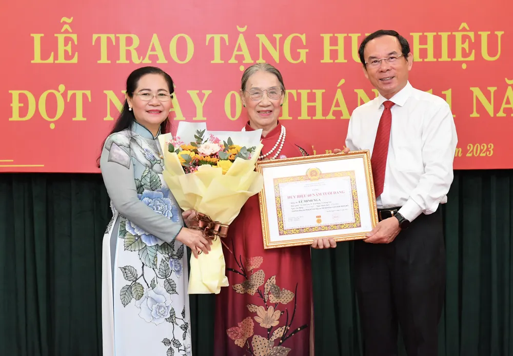 Bí thư Thành ủy TPHCM Nguyễn Văn Nên và Phó Bí thư Thành ủy TPHCM Nguyễn Thị Lệ trao Huy hiệu 60 năm tuổi Đảng đến đồng chí Lê Minh Nga. Ảnh: VIỆT DŨNG