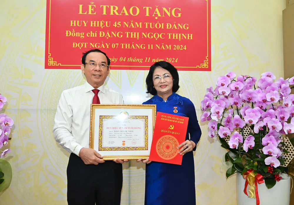 Bí thư Thành ủy TPHCM Nguyễn Văn Nên chúc mừng đồng chí Đặng Thị Ngọc Thịnh nhận Huy hiệu 45 năm tuổi Đảng. Ảnh: VIỆT DŨNG