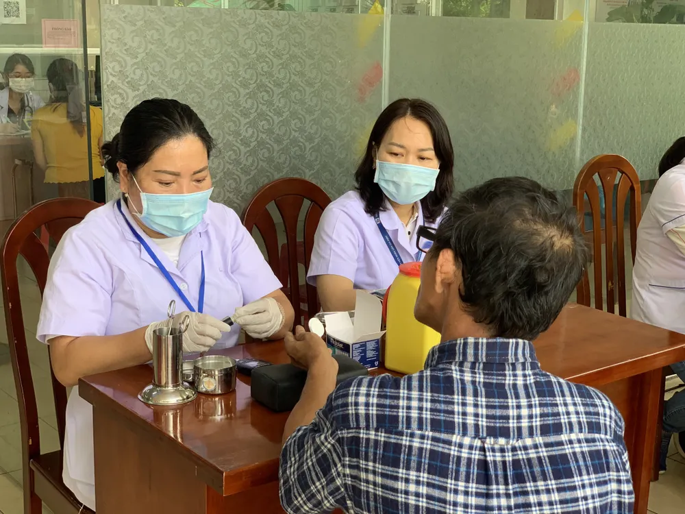 Bác sĩ lấy máu đo đường huyết cho người dân