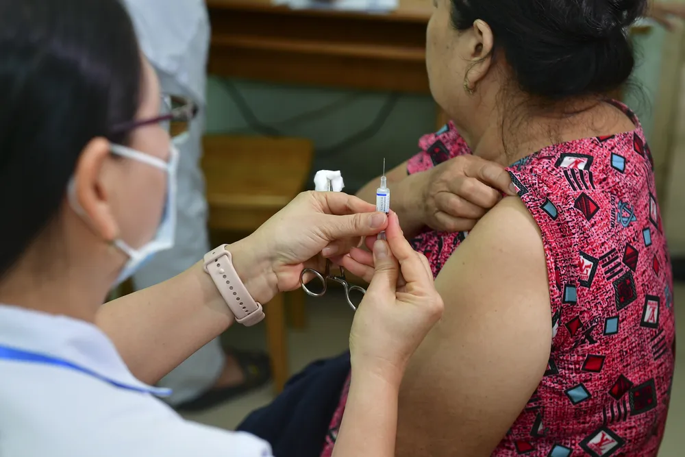 Bác sĩ tiêm vaccine cúm cho người cao tuổi tại Trạm y tế phường An Phú Đông