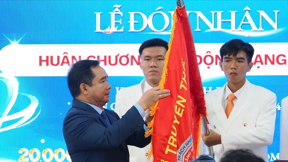 Chủ tịch UBND TPHCM Nguyễn Văn Được gắn Huân chương Lao động hạng Nhất lên cờ truyền thống Bệnh viện Răng Hàm Mặt TPHCM (Ảnh: HOÀNG HÙNG)