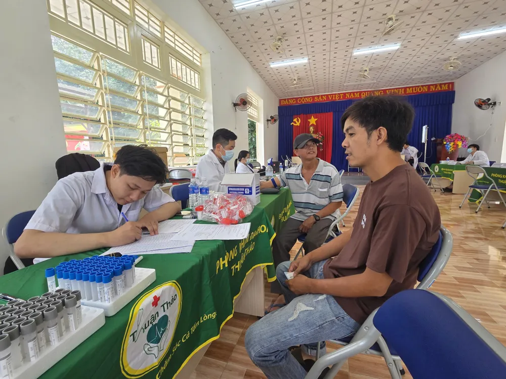 Nhân viên y tế khám sức khỏe cho người dân phường Chánh Phú Hòa (Ảnh: THÀNH AN)
