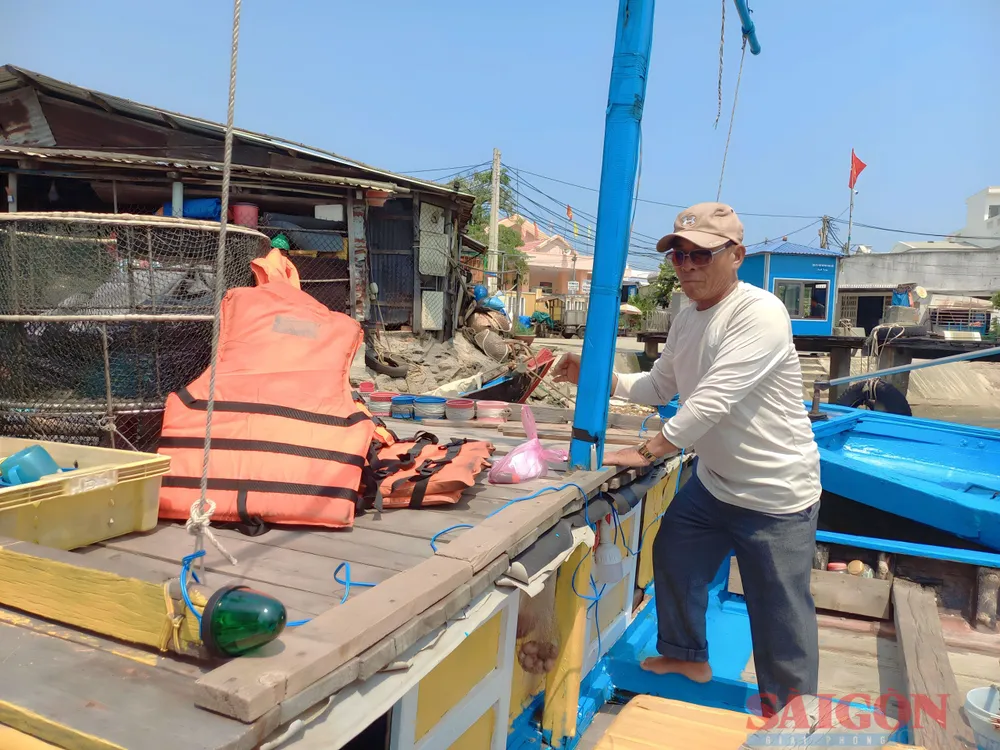 Ông Đỗ Quang Trung đang gắn thiết bị đèn xanh, đèn đỏ và trang bị phao cứu sinh trên tàu cá. Ảnh: NGUYỄN TRANG