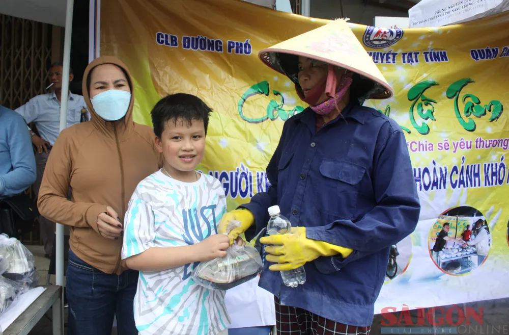 Những em nhỏ theo mẹ hỗ trợ gửi tận tay cơm cho mọi người. Ảnh: NGUYỄN TRANG