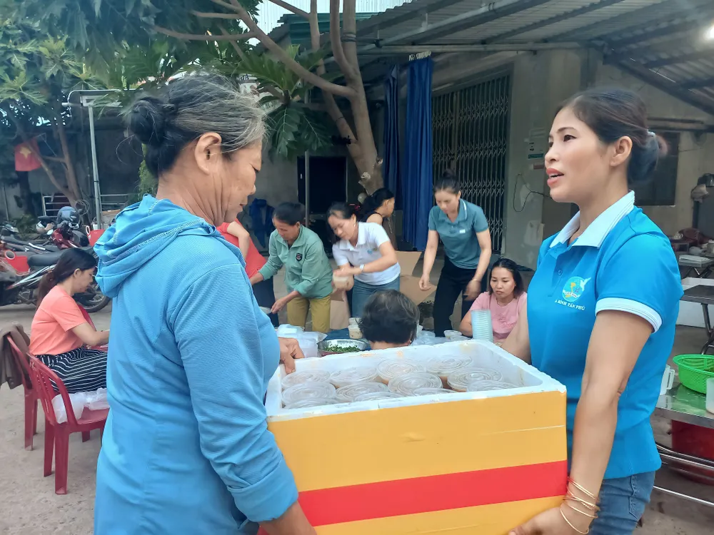 Chị Nhung, Chủ tịch Hội LHPN xã Bình Tân Phú, (bên phải) vận chuyển bữa sáng đến tận nhà người nghèo, khó khăn đi lại. Ảnh: NGUYỄN TRANG