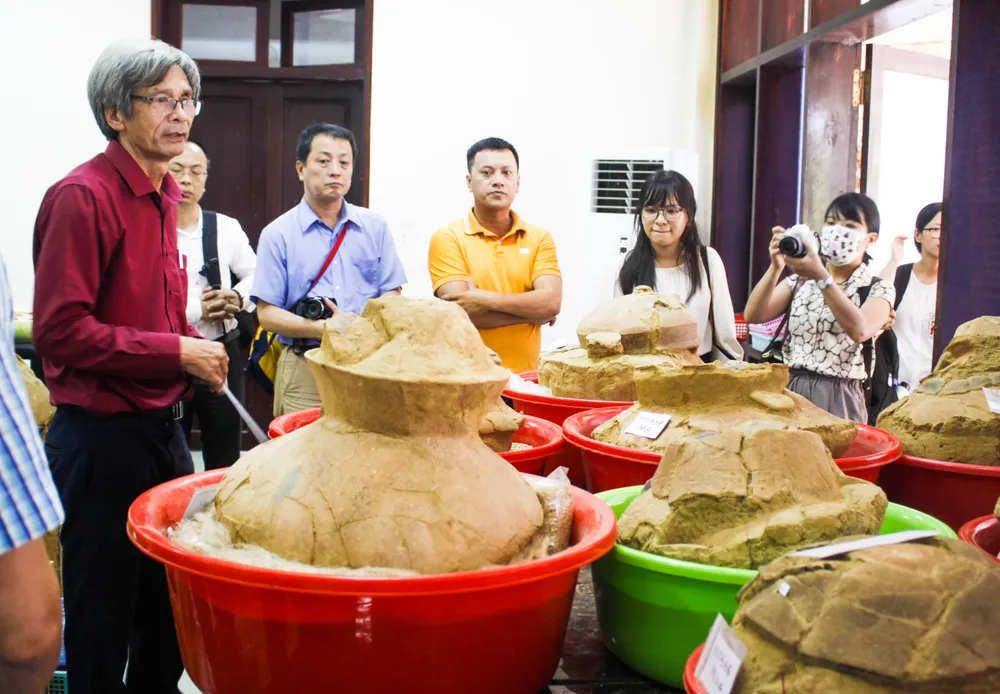 Tiến sĩ Đoàn Ngọc Khôi giới thiệu về các mộ chum được khai quật từ lòng hồ chứa nước Nước Trong và đến nay được bảo quản trong kho lạnh. Ảnh: NGUYỄN TRANG