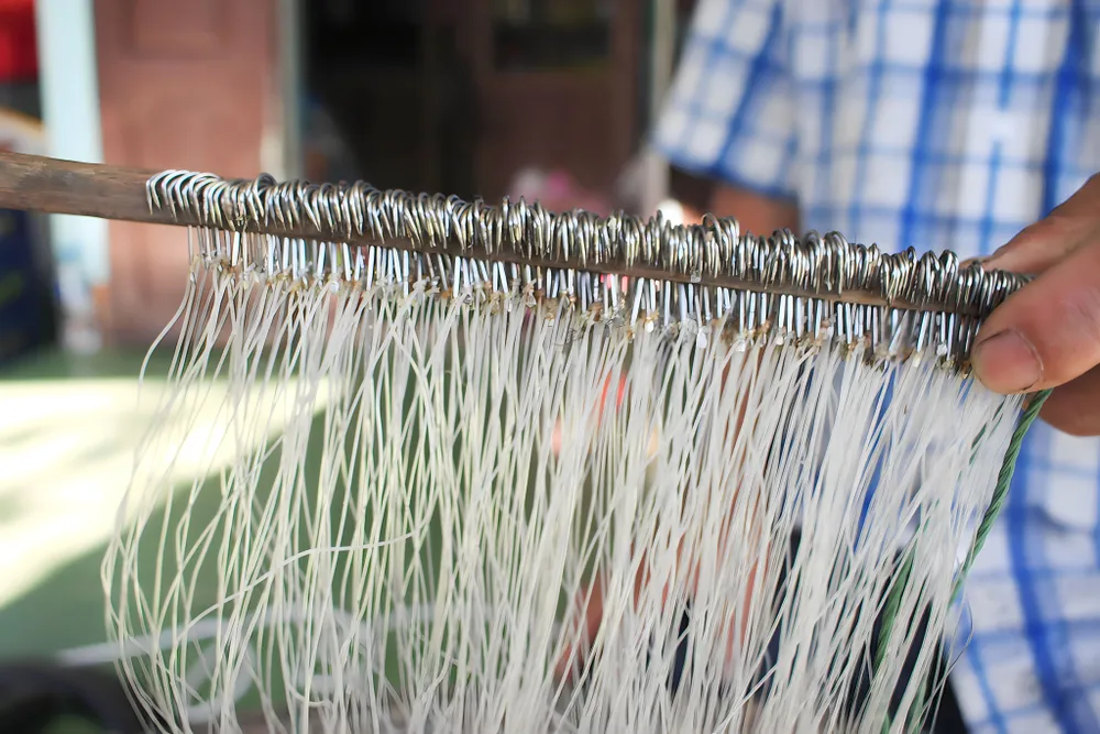 Gắn từng lưỡi câu vào dây lưới và kẹp vào nẹp tre, mỗi nẹp tre có khoảng 300-350 lưỡi câu. Ảnh: NGUYỄN TRANG Gắn từng lưỡi câu vào dây lưới và kẹp vào nẹp tre, mỗi nẹp tre có khoảng 300-350 lưỡi câu. Ảnh: NGUYỄN TRANG