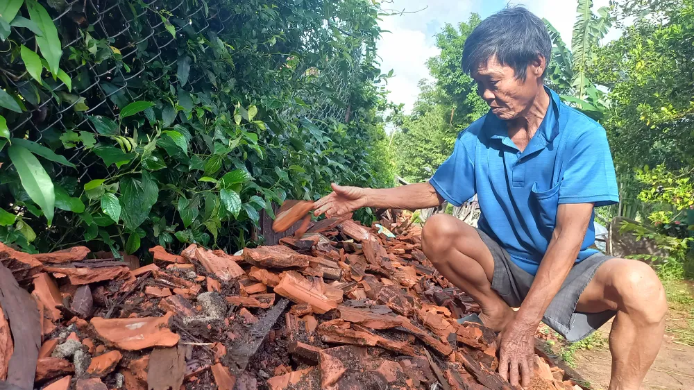 Ông Bá đang dọn dẹp gạch ngói sau thiệt hại xảy ra. Ảnh: NGUYỄN TRANG
