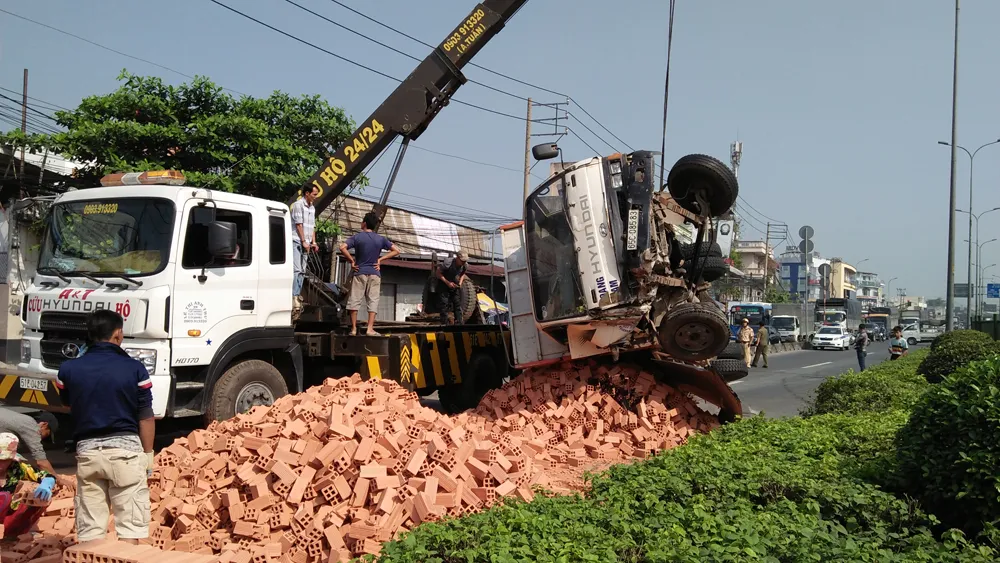 Xe tải chở gạch lật ngang, tài xế cùng phụ xe mắc kẹt kêu cứu trong cabin ảnh 1