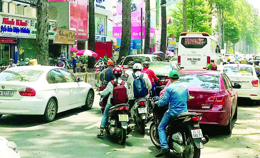  Cổng Bệnh viện Từ Dũ bị lấn chiếm nên các ô tô phải đón khách dưới lòng đường,  gây khó khăn cho người tham gia giao thông