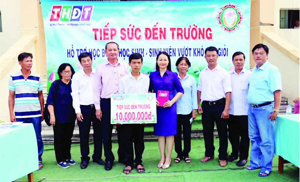 Ông Lưu Hoàng Tân - Chủ tịch, Giám đốc Công ty TNHH MTV Xổ số kiến thiết tỉnh Đồng Tháp (thứ 7 từ phải sang) trao học bổng cho em Vinh