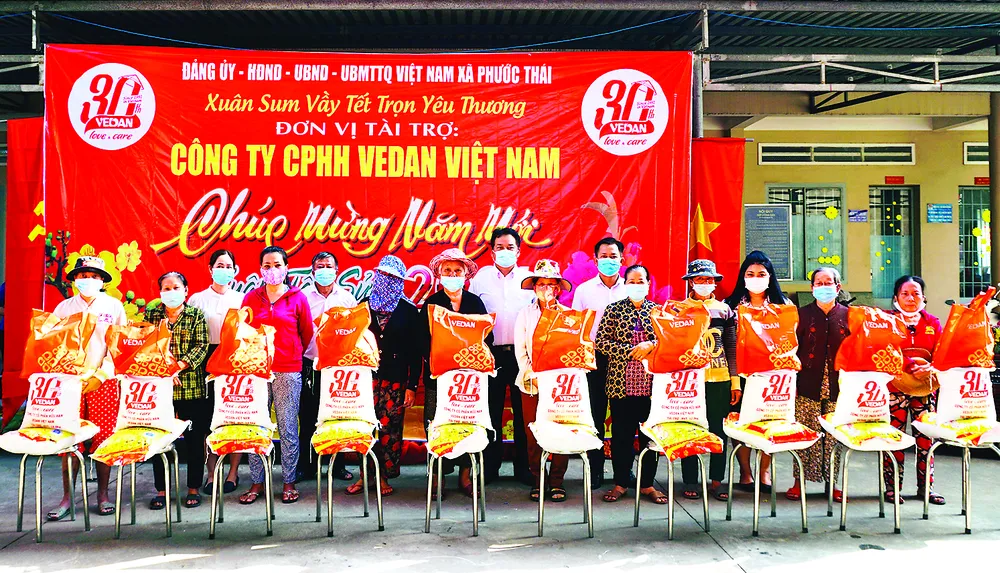 Đại diện công ty Vedan Việt nam (áo trắng giữa) cùng đại diện UBND xã Phước Thái, huyện Long thành, tỉnh Đồng Nai trao quà tết cho bà con tại địa phương