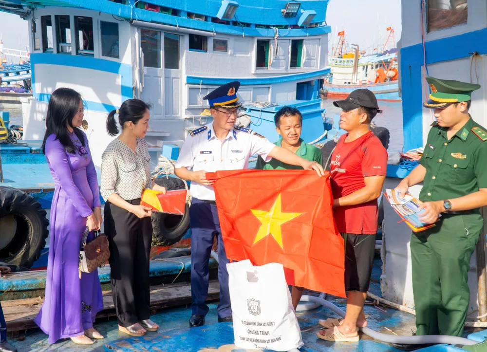 Đại tá Cao Xuân Quận, Phó Chính ủy Vùng Cảnh sát biển 3 cùng đại diện các lực lượng vũ trang đóng chân trên địa bàn, cấp ủy, chính quyền địa phương trao tặng cờ Tổ quốc quốc và các nhu yếu phẩm động viên ngư dân Bà Rịa - Vũng Tàu. Ảnh: MẠNH THẮNG