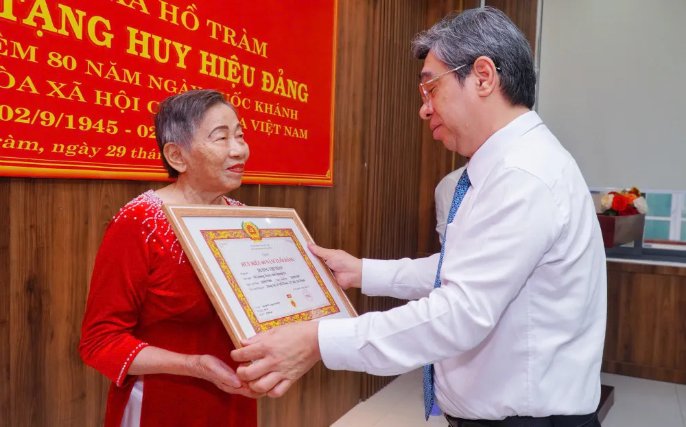 Đồng chí Nguyễn Phước Lộc, Phó Bí thư Thành ủy, Chủ tịch UBMTTQ Việt Nam TPHCM trao Huy hiệu 60 năm tuổi Đảng và tặng hoa chúc mừng đảng viên Dương Thị Xoan (xã Hồ Tràm)