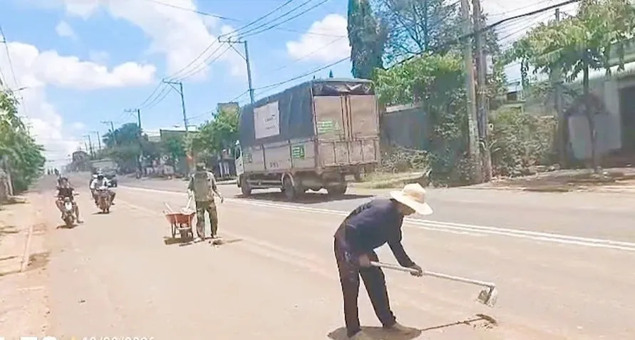 Đơn vị thi công và tài xế dọn dẹp đất, bùn sau khi lực lượng chức năng lập biên bản xử phạt. Ảnh: CSGT TPĐN