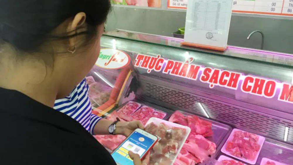 Khách hành sử dụng điện thoại thông minh quét mã vạch để biết được nguồn gốc xuất xứ thịt heo