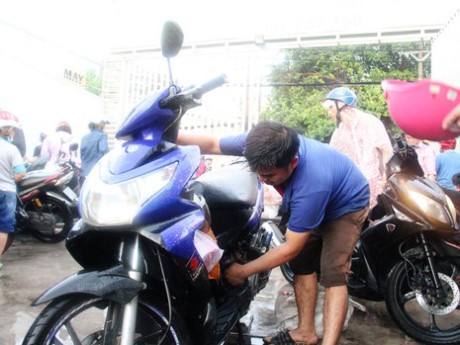 范如勝在雨中為路人免費修理車子。