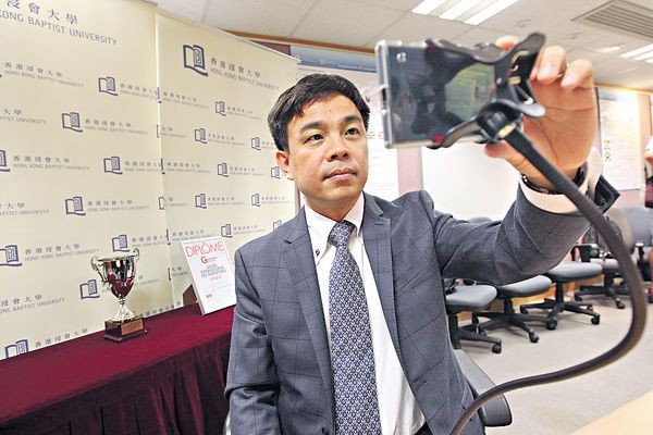 張曉明教授示範如何調節手機角度，令司機面容可被攝入鏡頭並被系統追蹤到。（圖源：互聯網）