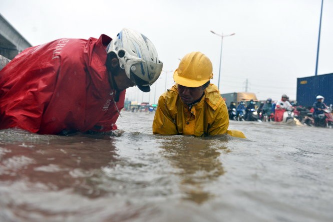 排水人員撬開河內公路迪哲橋附近路段的沙井蓋讓雨水排退。