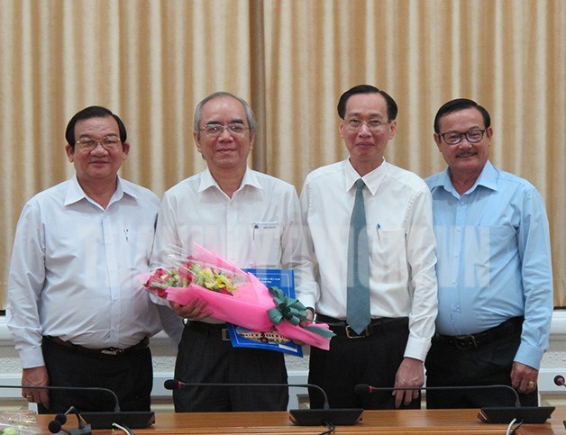 市人委會常務副主席黎清廉向市勞動與榮軍社會廳副廳長阮文熙(左二)送鮮花並頒發退休《決定》。（圖源：市黨部新聞網）