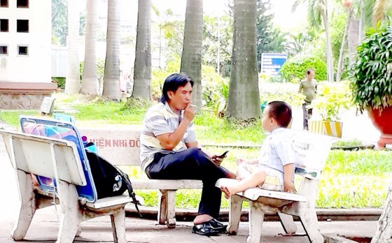 一病童家長在第二兒童醫院庭院裏對著孩子抽煙。