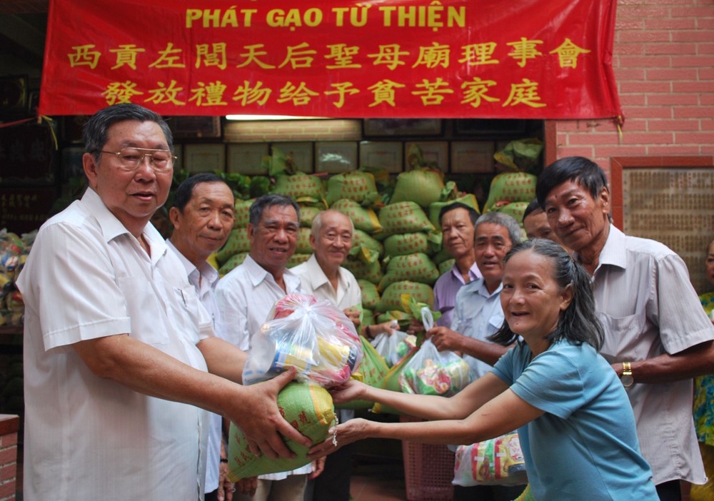 西貢左閭天后聖母廟會長李祺鏢(左一) 與理事們向貧困同胞贈送禮物。